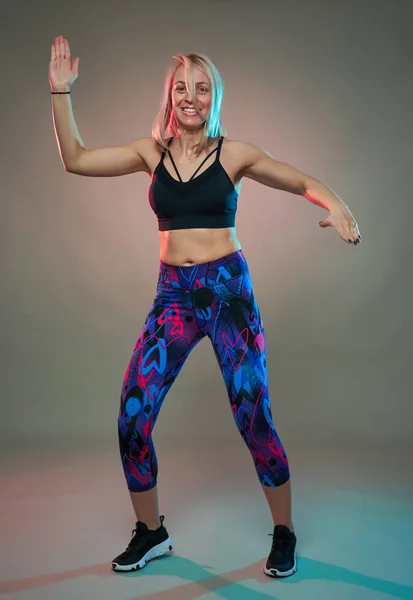 Fitness model doing aerobic exercises and dancing, studio shot