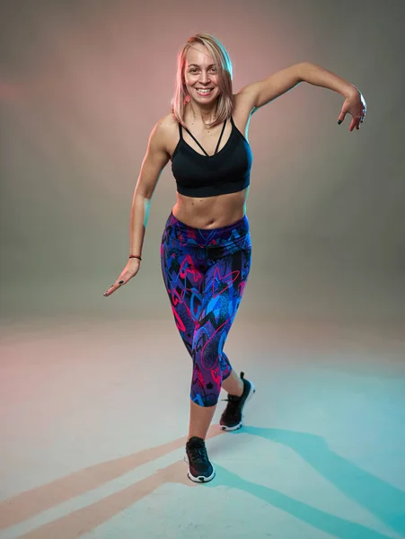 Fitness model doing aerobic exercises and dancing, studio shot