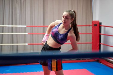 Kickbox dövüşçüsü kız antrenmandan önce geriniyor.
