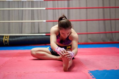 Kickbox dövüşçüsü kız antrenmandan önce geriniyor.