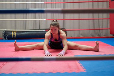 Kickbox dövüşçüsü kız antrenmandan önce geriniyor.