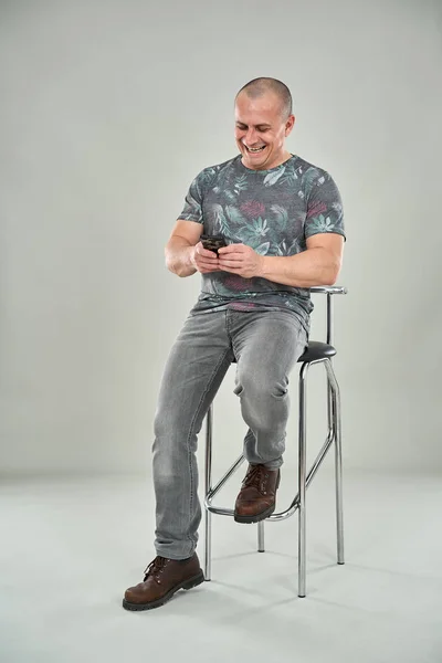 Feliz Homem Caucasiano Divertido Usando Celular Enquanto Sentado Uma Cadeira — Fotografia de Stock