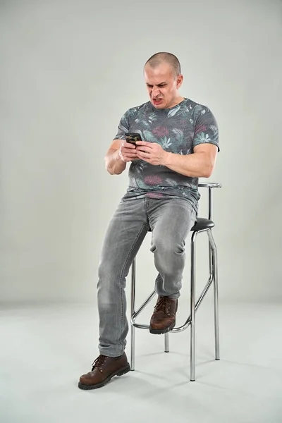 Angry Caucasian Man Using Cellphone While Sitting Tall Chair — Stock Photo, Image