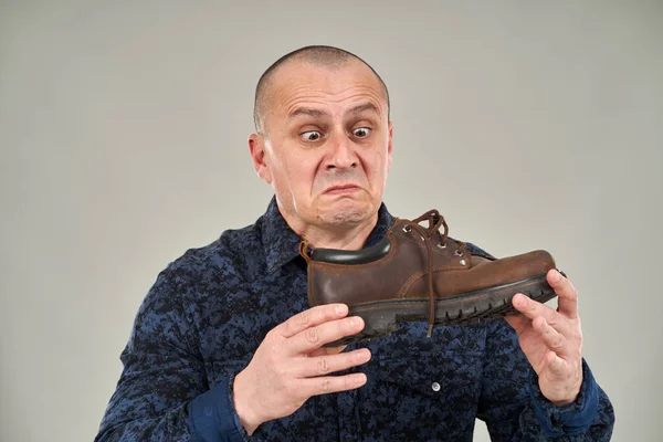 コーカシア人の男は嫌悪感の表情で臭い靴を保持 — ストック写真