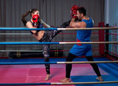 Kadın kickboksör ringde koçuyla yumruk tokuşturuyor.