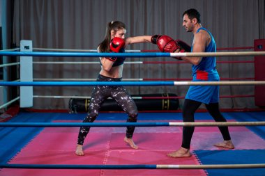 Kadın kickboksör ringde koçuyla yumruk tokuşturuyor.