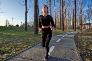 Parkta koşan eşofmanlı atletik bir kadın.