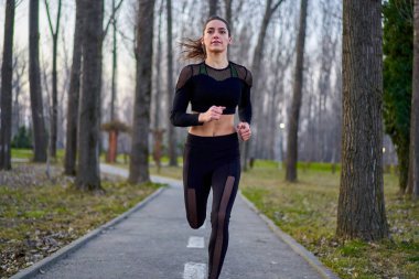 Parkta koşan eşofmanlı atletik bir kadın.