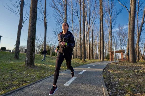 Athletic woman in track suit running in the park