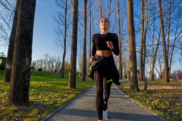 Athletic woman in track suit running in the park