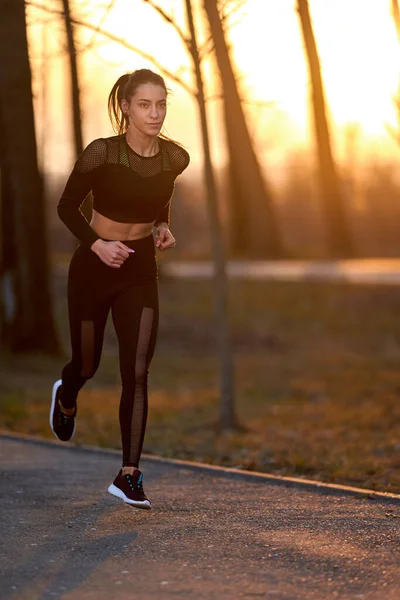 Athletic woman in track suit running in the park