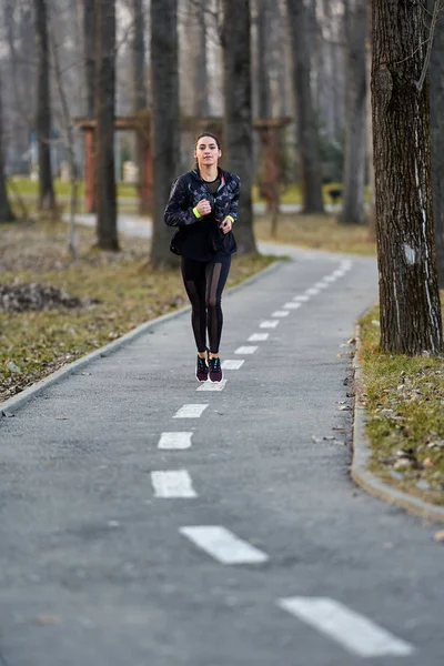 Athletic woman in track suit running in the park