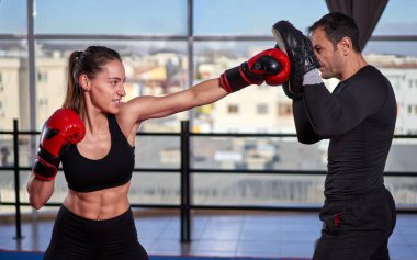 Genç boksör kadın koçuyla yumruk tokuşturuyor.