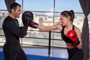 Genç boksör kadın koçuyla yumruk tokuşturuyor.