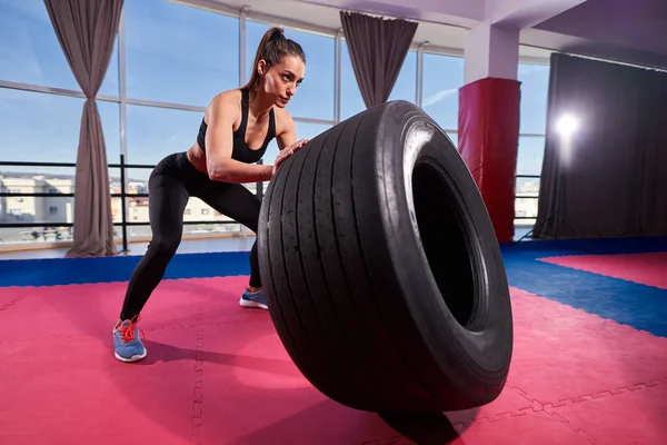 Atletická Mladá Žena Dělá Pneumatiky Salta Tělocvičně — Stock fotografie