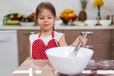 Mutfakta yemek pişiren önlüklü sevimli küçük kız.