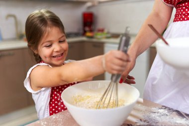 Küçük kız mutfakta annesine yardım ediyor.