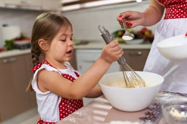 Küçük kız mutfakta annesine yardım ediyor.