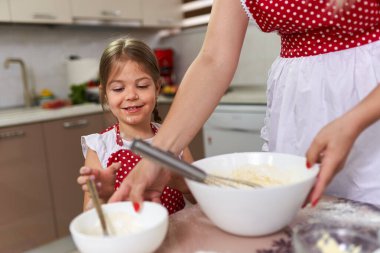 Küçük kız mutfakta annesine yardım ediyor.