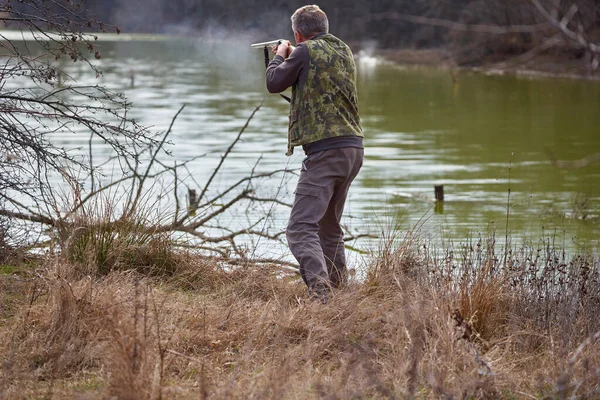 Κυνηγός Που Πυροβολεί Αγριόπαπιες Μια Λίμνη — Φωτογραφία Αρχείου