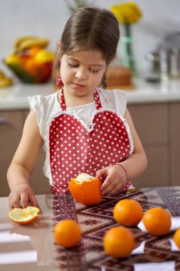 Genç kız mutfakta portakal soyuyordu.