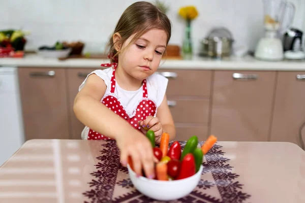 小さな女の子が様々な野菜をボウルに入れて — ストック写真