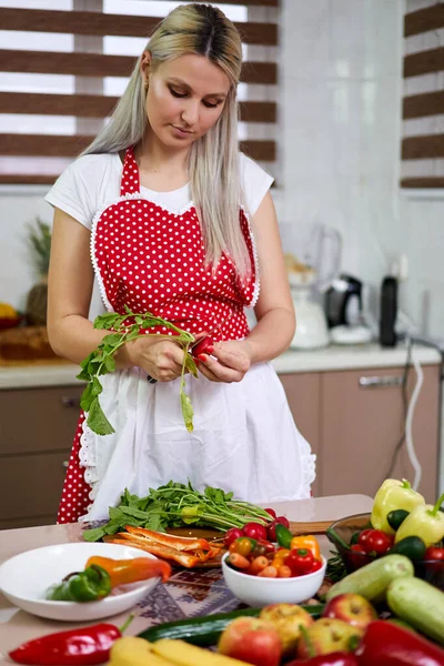 若いです女性で彼女の台所で野菜や果物の束 — ストック写真