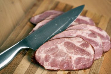 Ahşap bir tahtada dilimlenmiş şefin bıçağı ve domuz boynu.