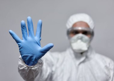 Coronavirus 'a karşı koruyucu giysili bir adam dur işareti yapıyor.