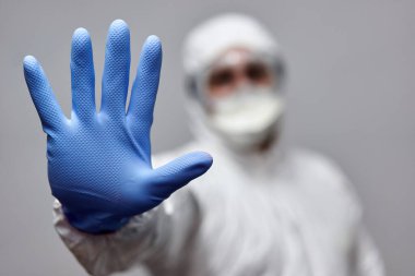 Coronavirus 'a karşı koruyucu giysili bir adam dur işareti yapıyor.