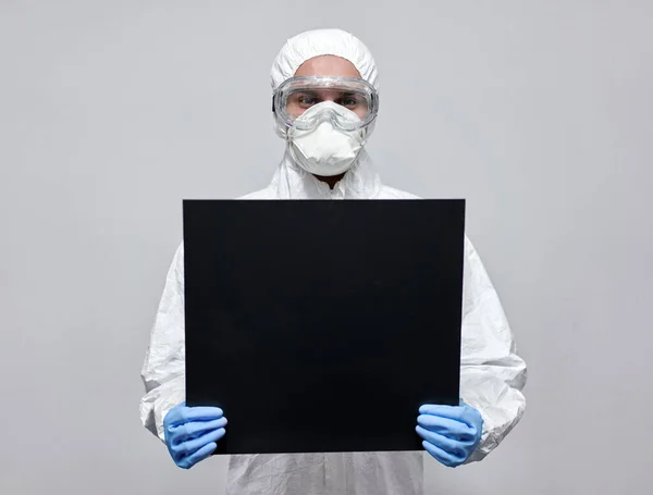 Man in hazard overall suit with empty black cardboard with copyspace