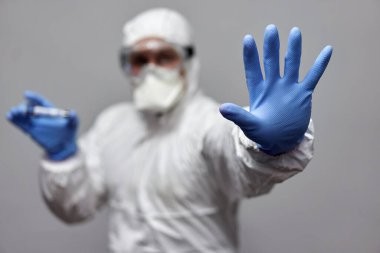 Coronavirus 'a karşı koruyucu giysili bir adam dur işareti yapıyor.