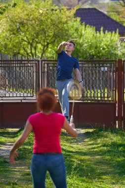 Anne ve oğlu evin avlusunda badminton oynuyorlar.