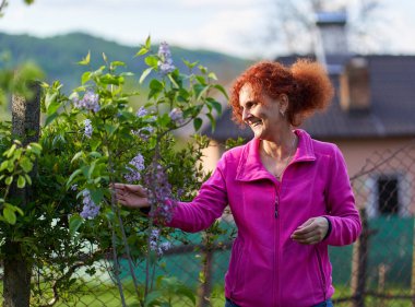 Güzel kıvırcık saçlı kadın leylak çalılığında