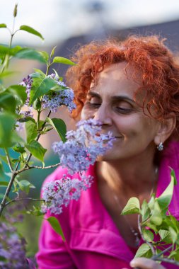 Güzel kıvırcık saçlı kadın leylak çalılığında
