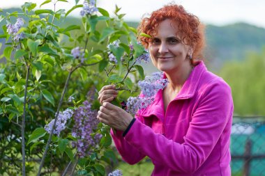 Güzel kıvırcık saçlı kadın leylak çalılığında