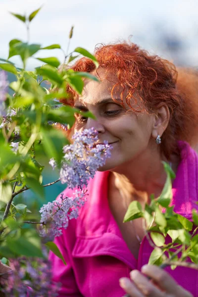 Güzel kıvırcık saçlı kadın leylak çalılığında