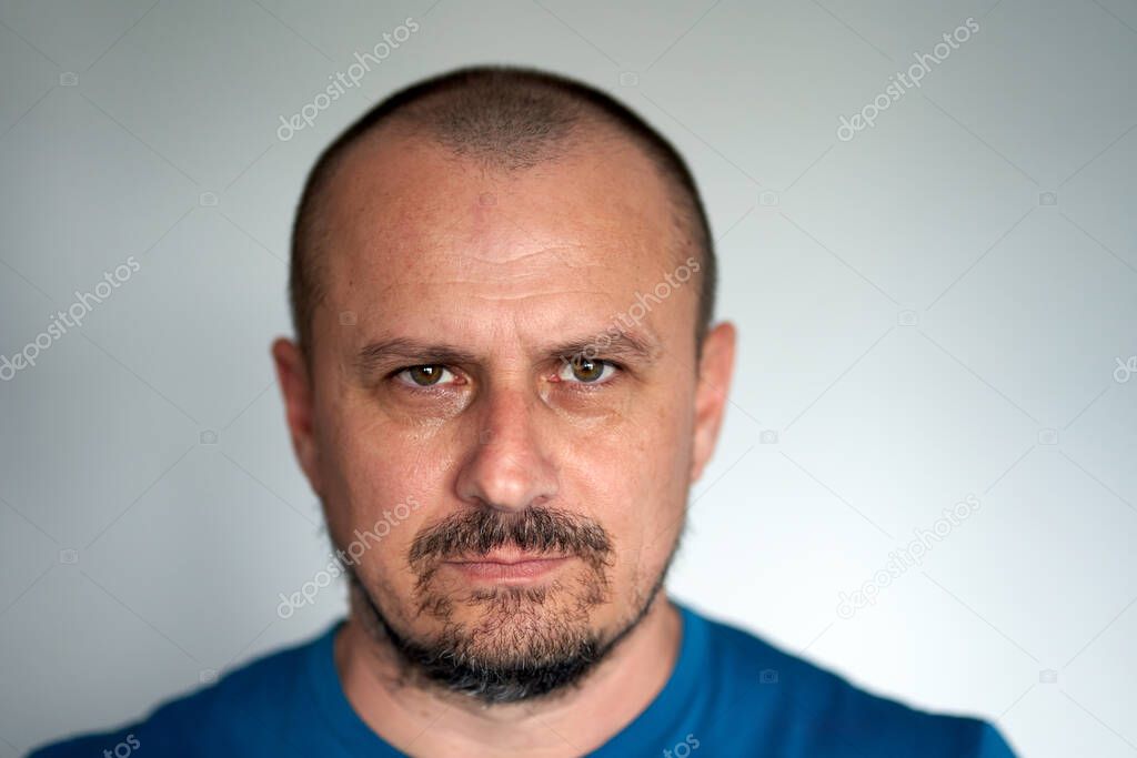 Closeup of a man with black beard and hostile expression