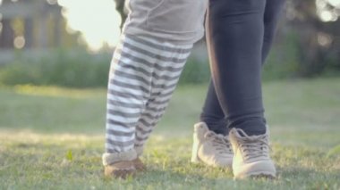 İlk anne yardımı ile çim açık basamaklardan bebeğim. Yürümeye başlayan çocuk ve anne güneşli bir düşük açılı yavaş çekim.