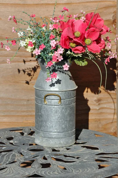 Pink flowers in metal milk can — Stock Photo, Image