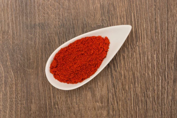 Röd paprika pulver över trä bakgrund — Stockfoto