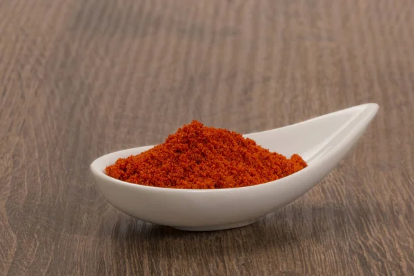 Röd paprika pulver över trä bakgrund — Stockfoto