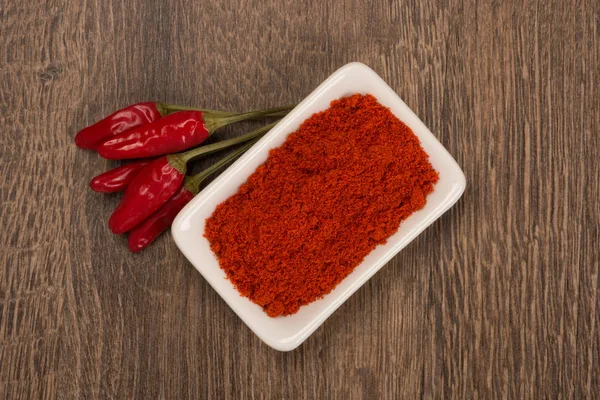 Gemahlene und ganze Paprika auf rustikalem Holztisch — Stockfoto