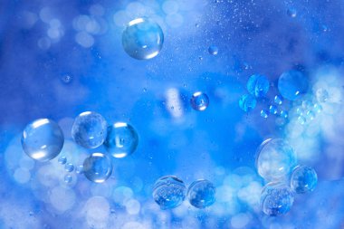 Deniz suyunda küçük hava kabarcıkları. Makro fotoğraf. Mavi soyut arka plan. Aydınlatılmış sıvı yüzey.