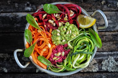 Lezzetli kabak, pancar ve soslu havuçlu erişte, humus ve fındık. Koyu ahşap arka planda. Temiz yemek, diyet, vejetaryen gıda konsepti