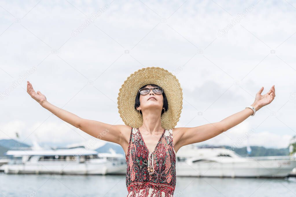 traveling Asian woman with hat open arms