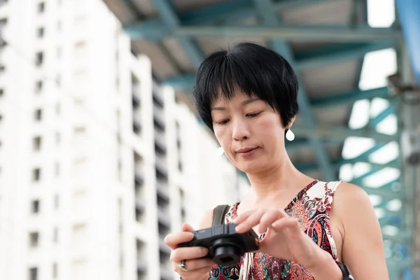 Dojrzały Asian kobieta przy pomocy cyfrowy aparat fotograficzny — Zdjęcie stockowe