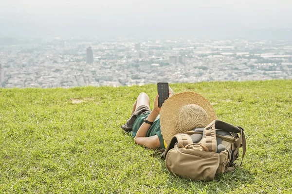 Vrouw liggen op grasland en met behulp van mobiele telefoon — Stockfoto