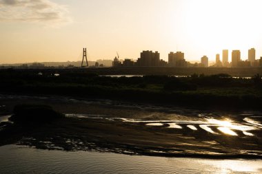 gün batımında nehir ile binaların silueti 