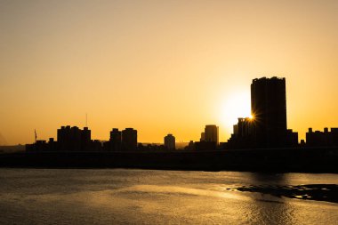 gün batımında nehir ile binaların silueti 